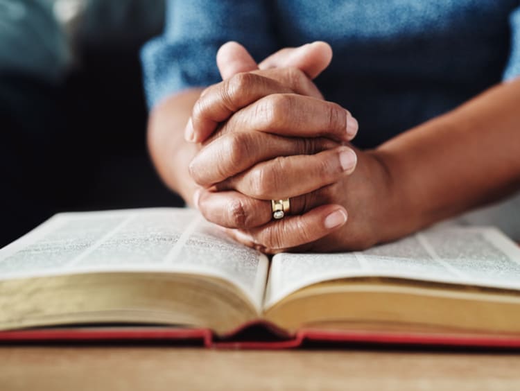Hands praying over Bible