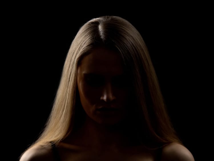 person standing in a dark area with light on one side of their face