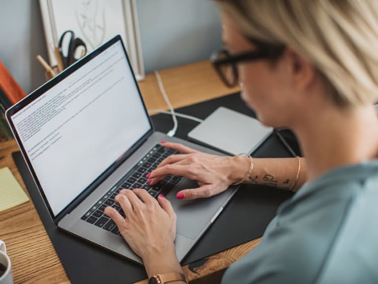 Female book publisher writing story on laptop from home office