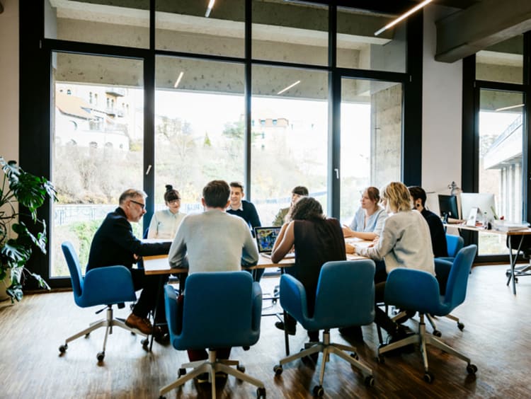 Business meeting in a large board room with tall windows