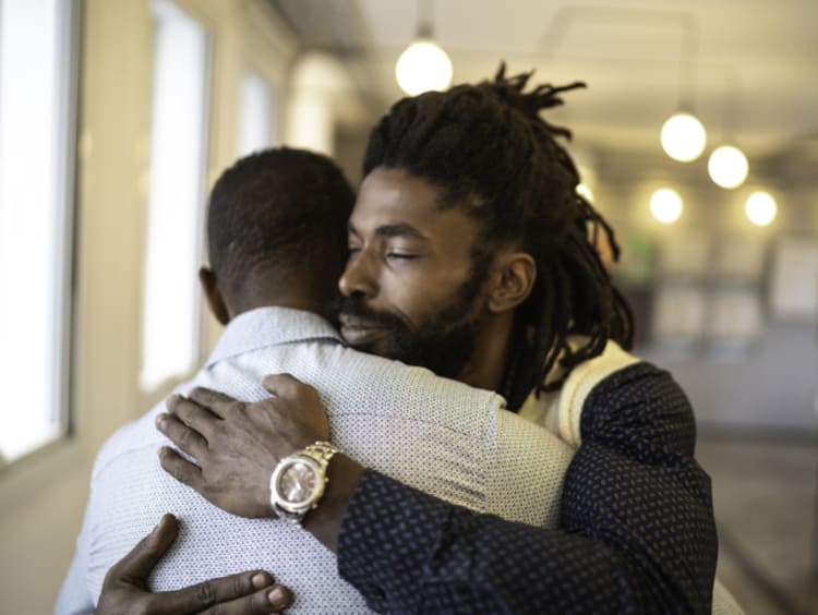 Two guys hugging and supporting each other