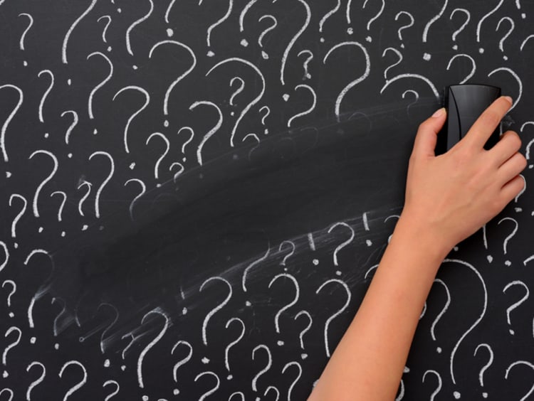 Hand erasing question marks on chalkboard