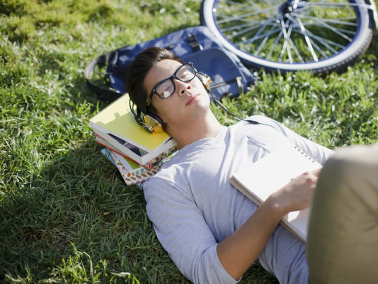 Student listening to music and relaxing on grass outside