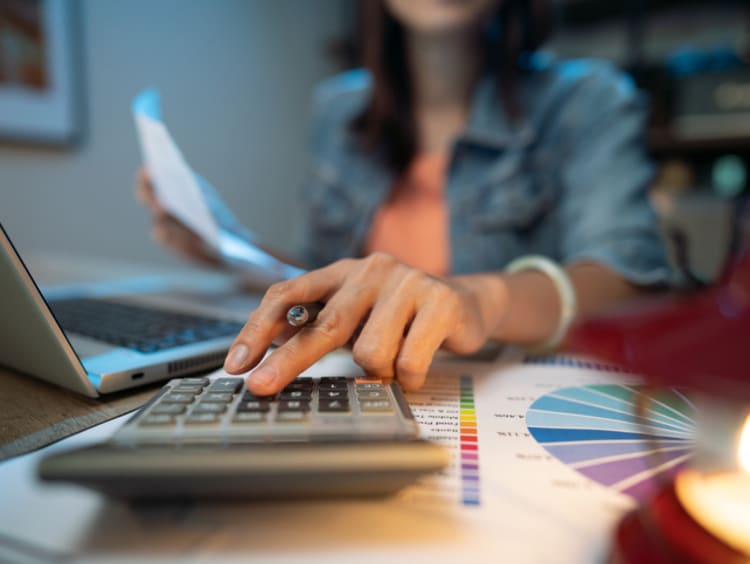 Woman typing on calculator going over finances