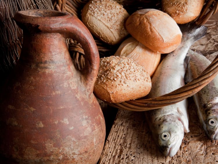 Loaves of bread and fish with old clay pitcher as a model for one of the miracles of Jesus