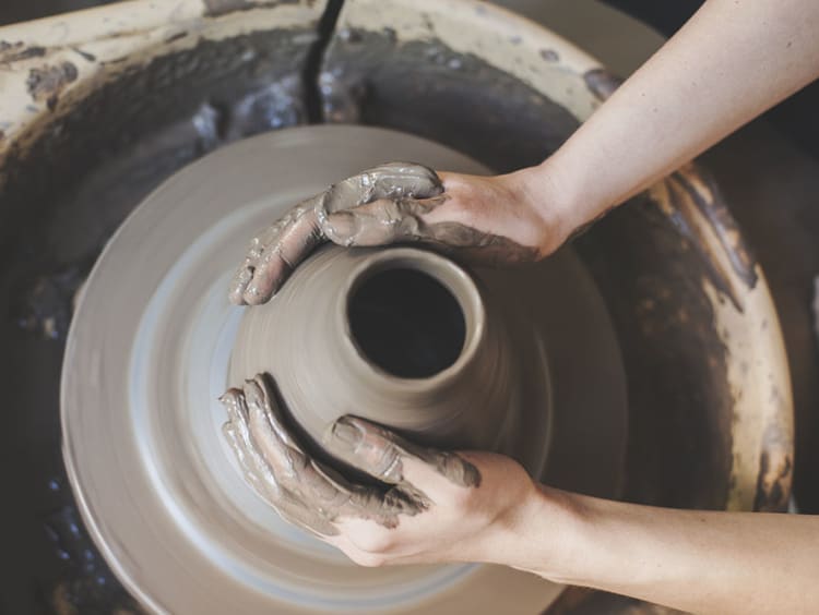Pair of hands carefully mold a jar of clay