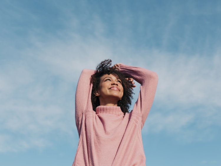 Woman smiles and looks up at the blue sky