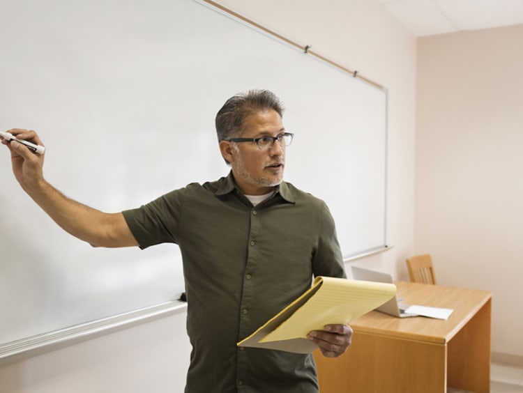 Male teacher writing on whiteboard to teach students how to learn to read