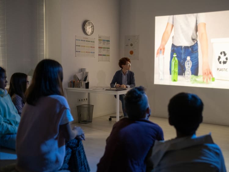 A teacher presenting an anticipatory set about recycling through a video