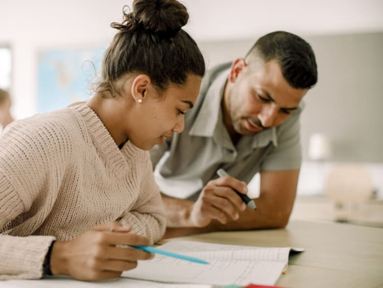 female student and male teacher reading together in classroom