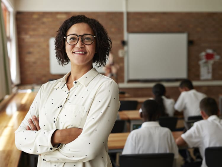 female teacher smiling in front of students in classroom
