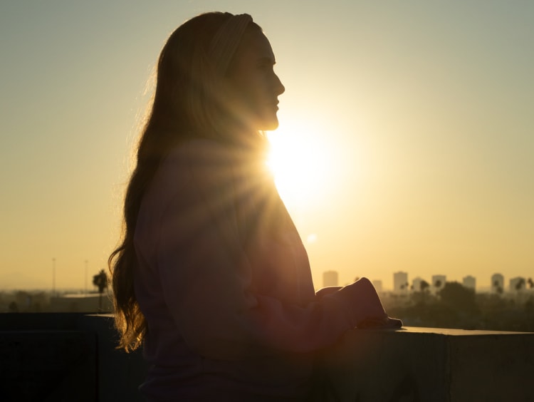 Female silhouette with sun setting behind the girl's shadow with the Phoenix downtown landscape in the distance