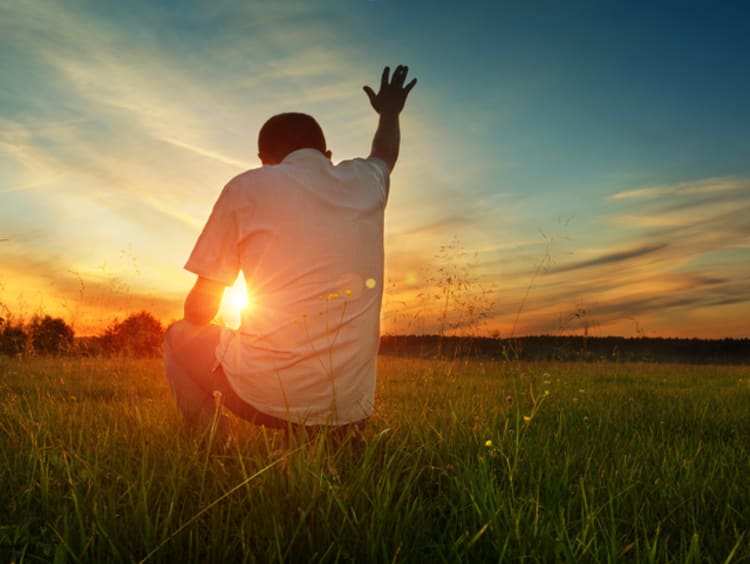 Man prays to God in grassfield