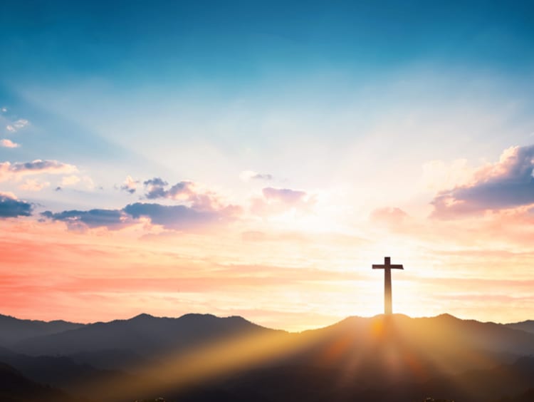 A cross stands in front of behind a beautiful sunset