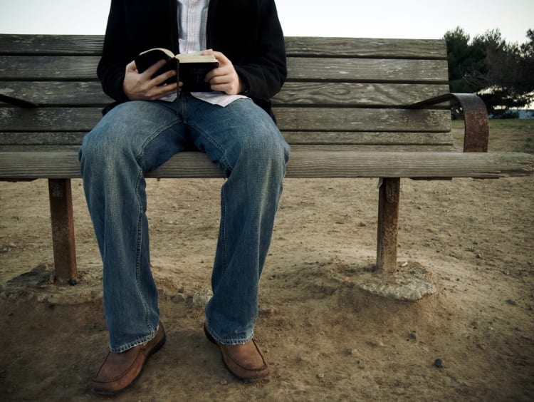 guy sitting on bench with open Bible