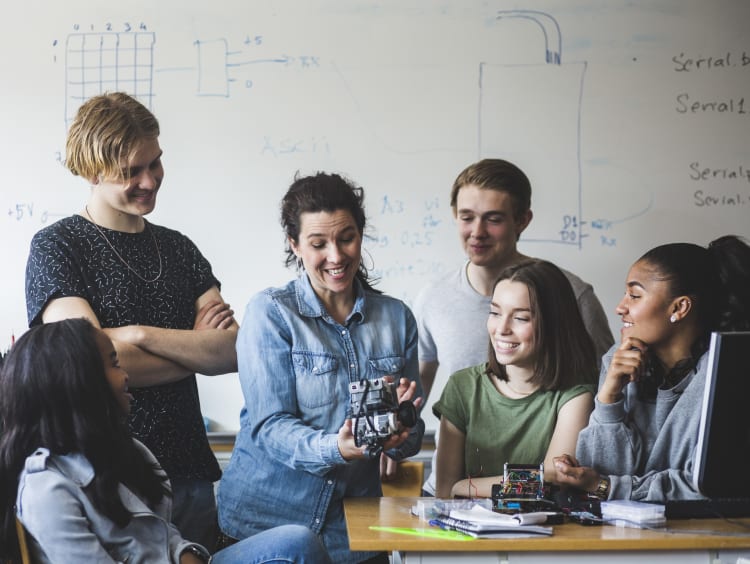 High school students working on machinery with teacher