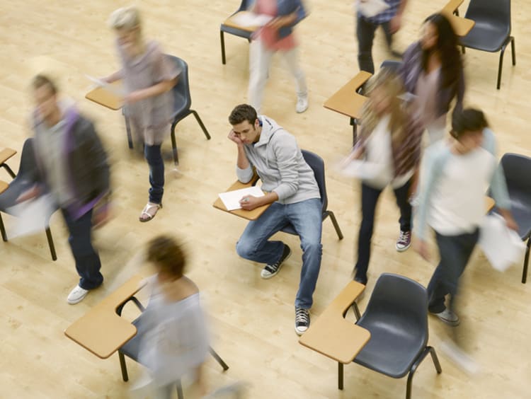 Stressed student at a desk surrounded by other students