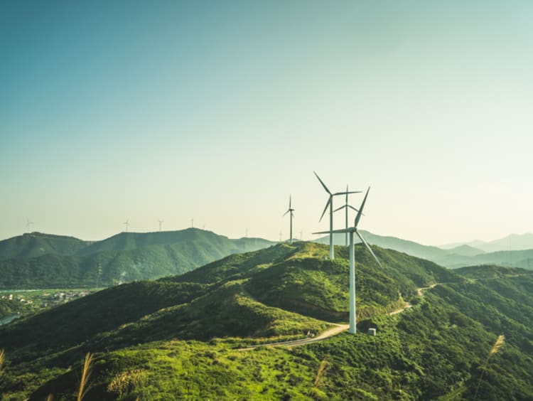 Wind mills on mountain range with overcast sky