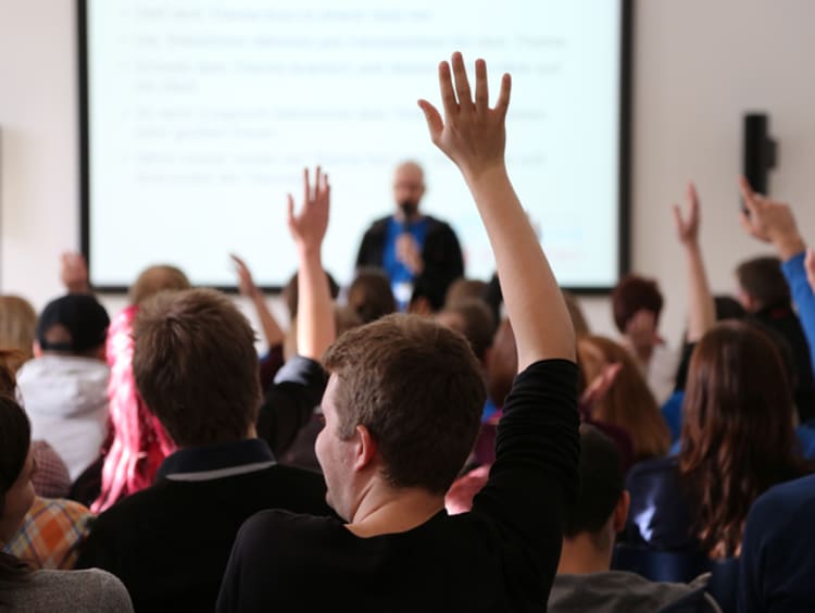 honors students raising their hands in class