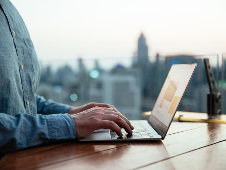 A doctoral student typing on computer by a window