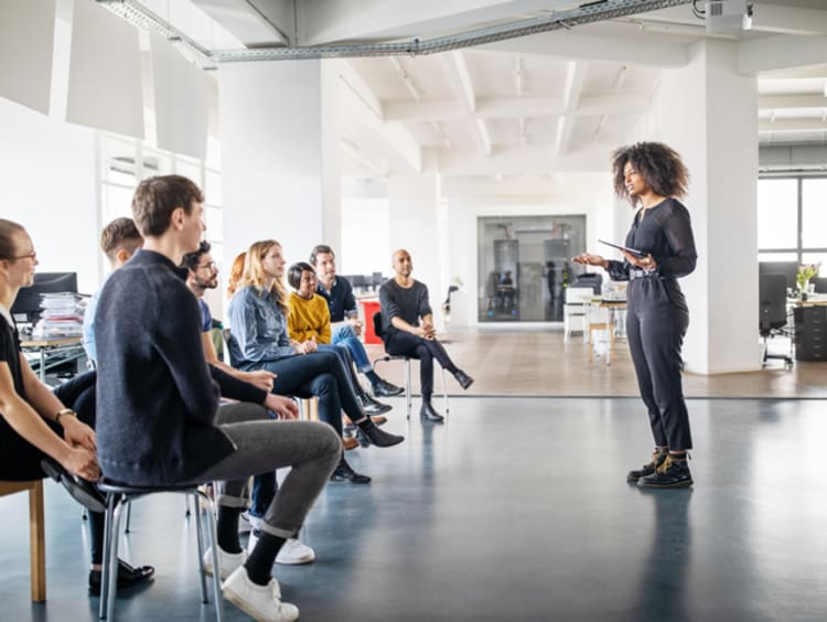 Woman speaker addressing audience in open office