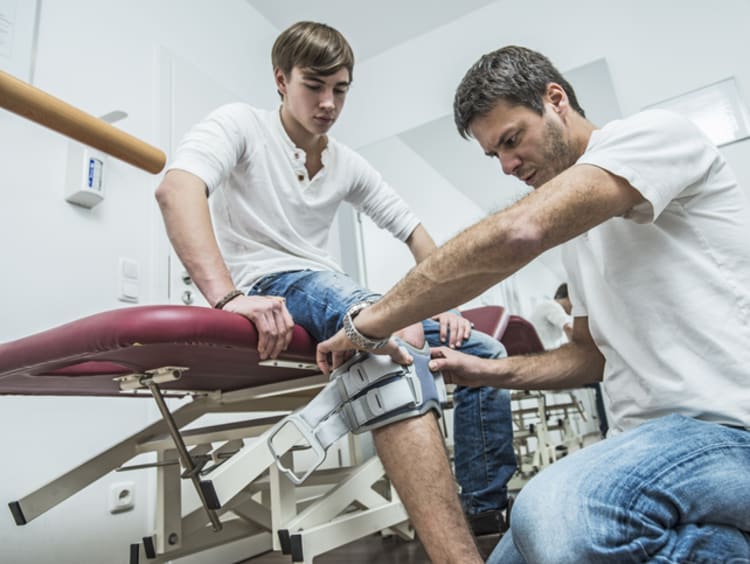 physical therapist looking at a patient's knee