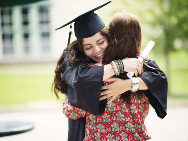 college grad in cap and gown hugging family member