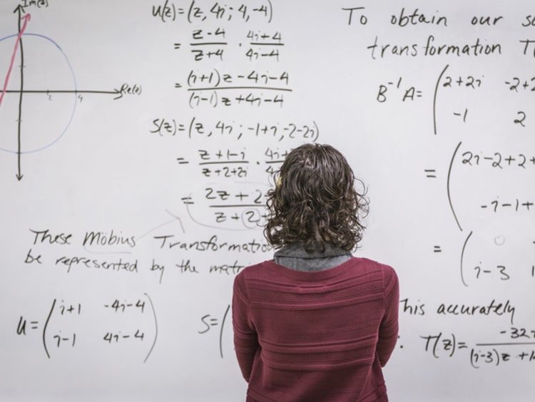 math teacher facing the board in reflection