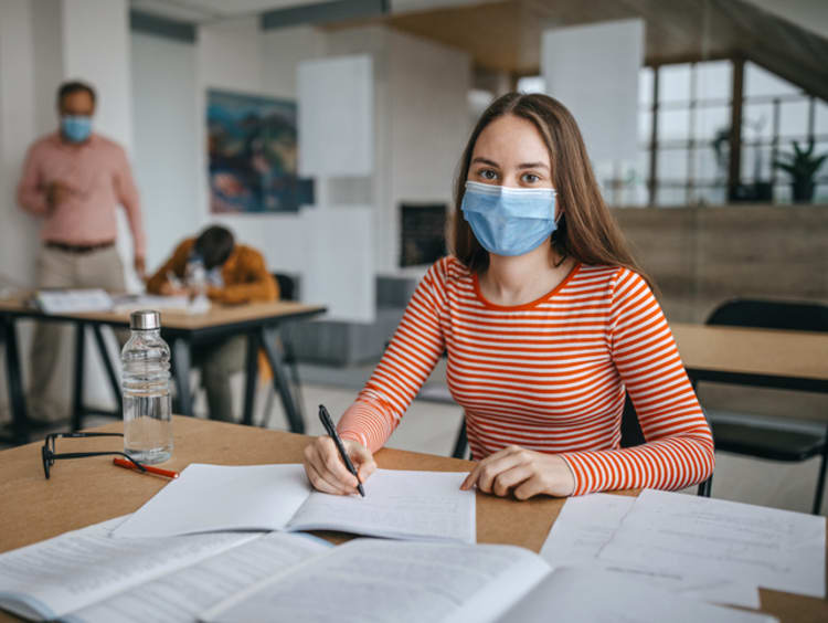 Girl in a mask working on homework