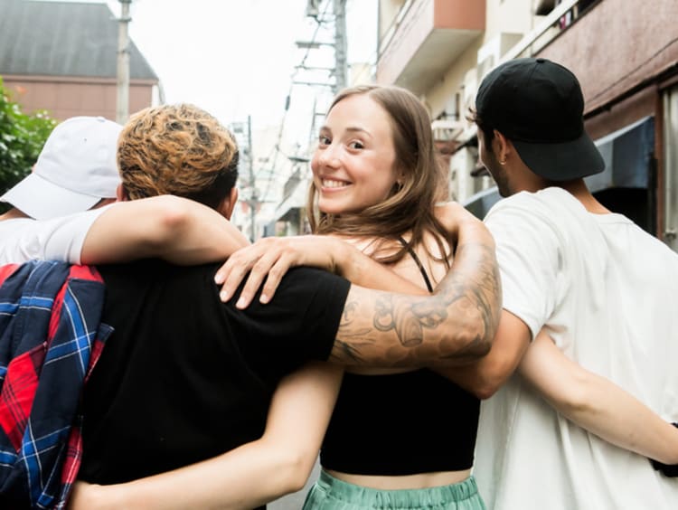 Group of friends walk down a narrow street with arms interlinked