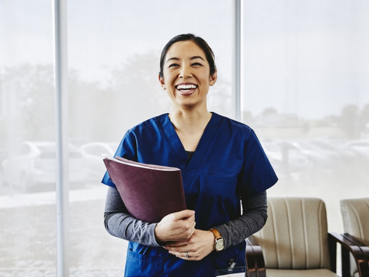 Nurse smiling and holding paperwork in office