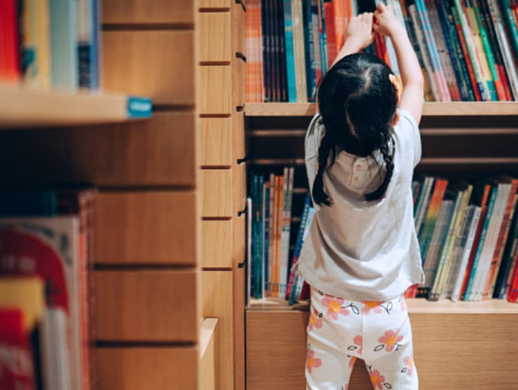 little girl reaching for books