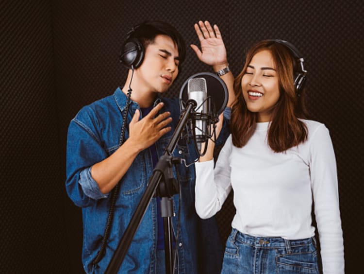 Male and female session musicians singing together in studio