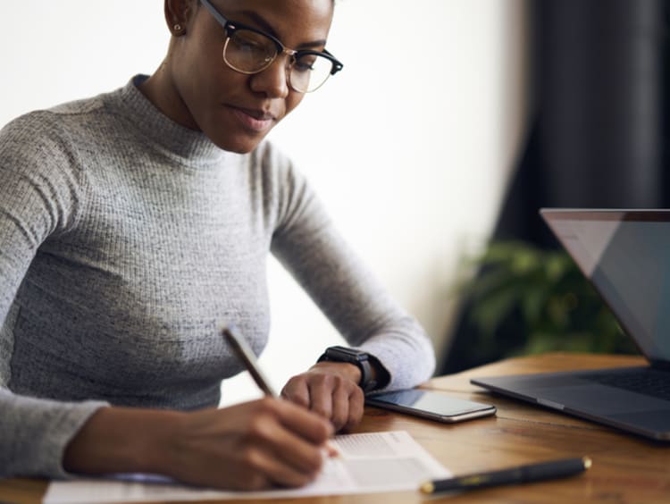 Young African American women sitting with her laptop and paper editing.