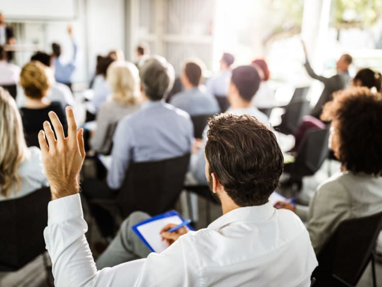 student raising hand in professional setting