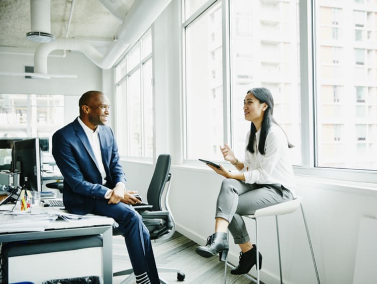 Man and woman talking and sitting across from each other in an office