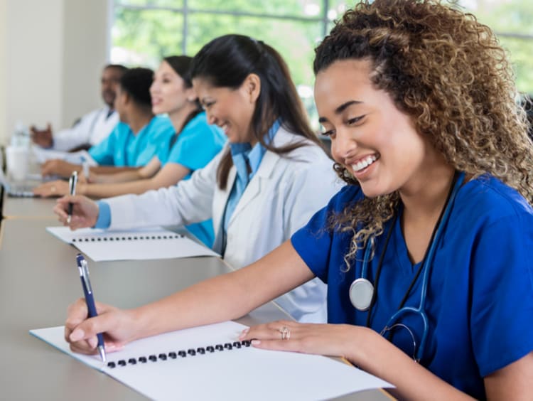 Nursing student writing on paper in class with peers