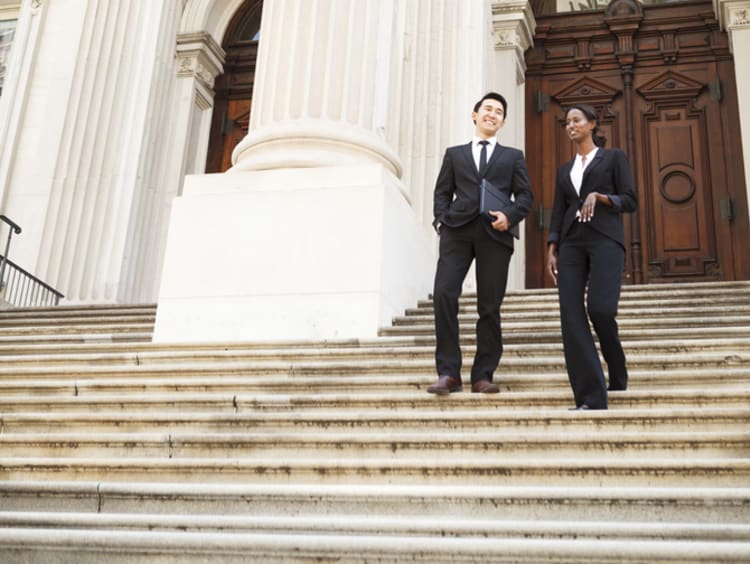 Two politicians on the steps of a courthouse talking together.