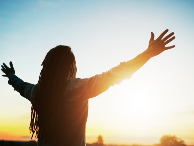  Man with arms outstretched at sunset - stock photo