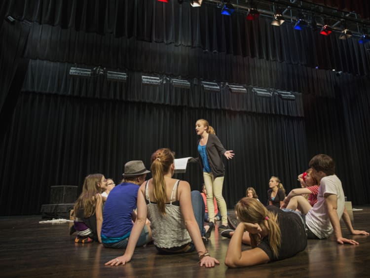 theatre student rehearsing in front of other students on stage