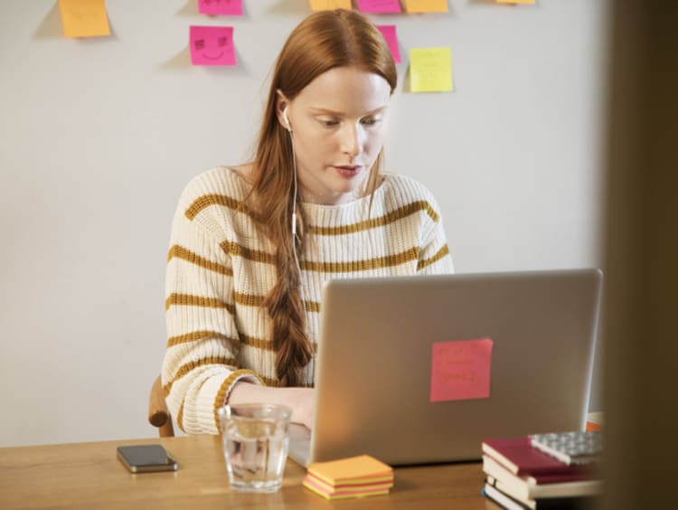 Female editor sitting at a desk with her laptop and notes