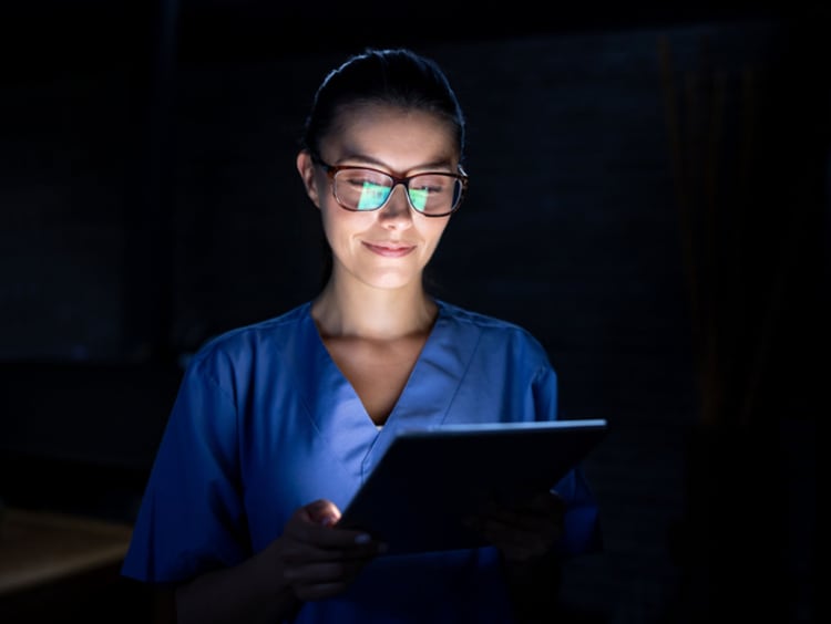 Portrait of a Latin American nurse looking at the results of a medical exam at night on a tablet - healthcare and medicine concepts