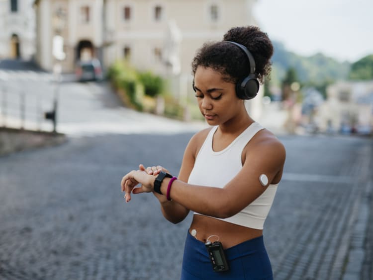 Beautiful diabetic girl in activewear checking her performance on smartwatch. Diabetic teenage girl with continuous glucose monitor and insulin pump exercising. Concept of daily life with chronic illness, diabetes for teenagers.