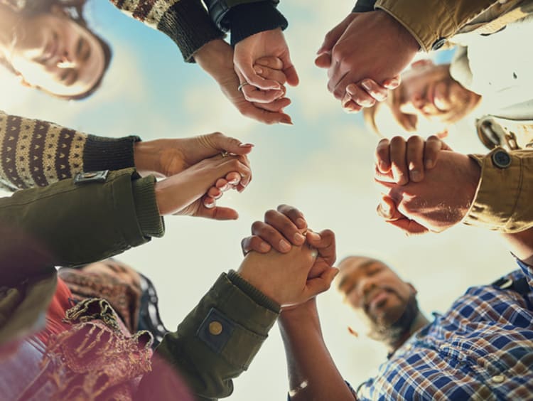 Shot of a group of friends putting their hands together in prayer