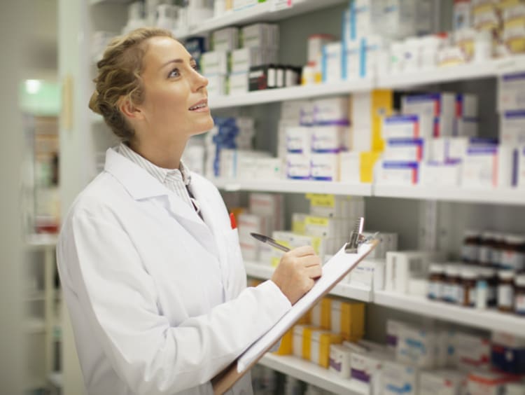 Pharmacist writing on clipboard - stock photo