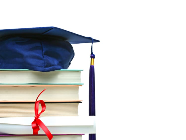 graduation cap on top of books and a diploma