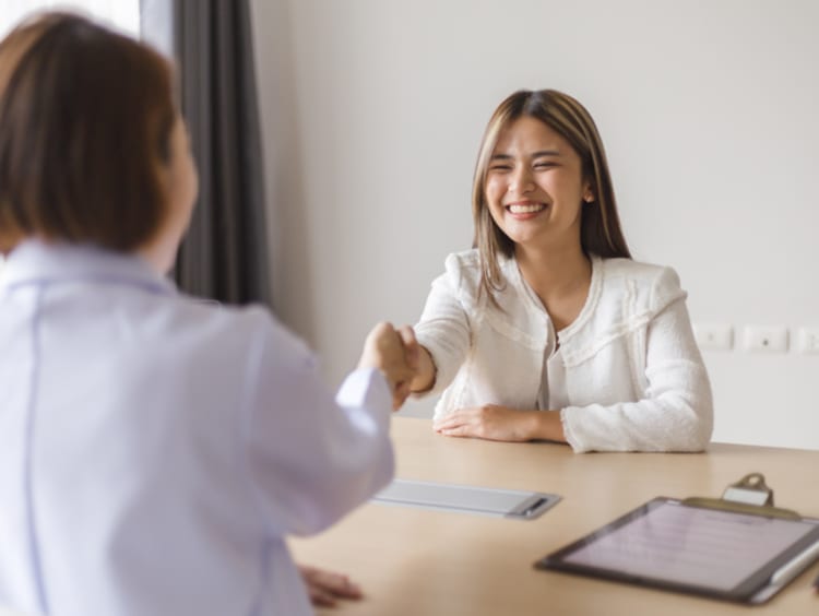 A young female being interviewed and shaking hands with the interviewer