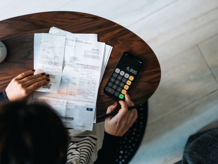 Person entering numbers in a calculator while holding papers in other hand