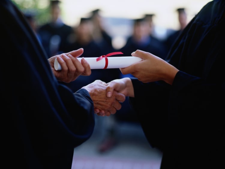 Graduate receiving a diploma, close-up of hands - stock photo