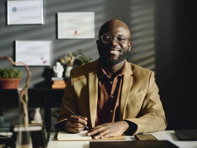 Male professional at desk with degrees on wall